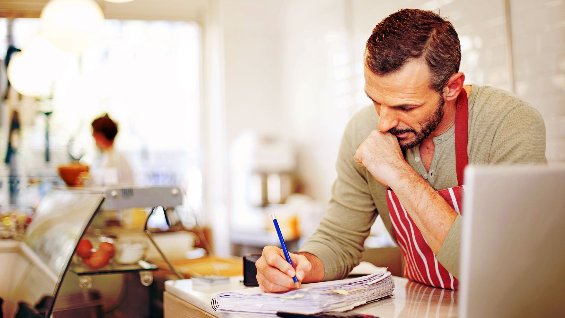 Male business owner in apron doing paperwork