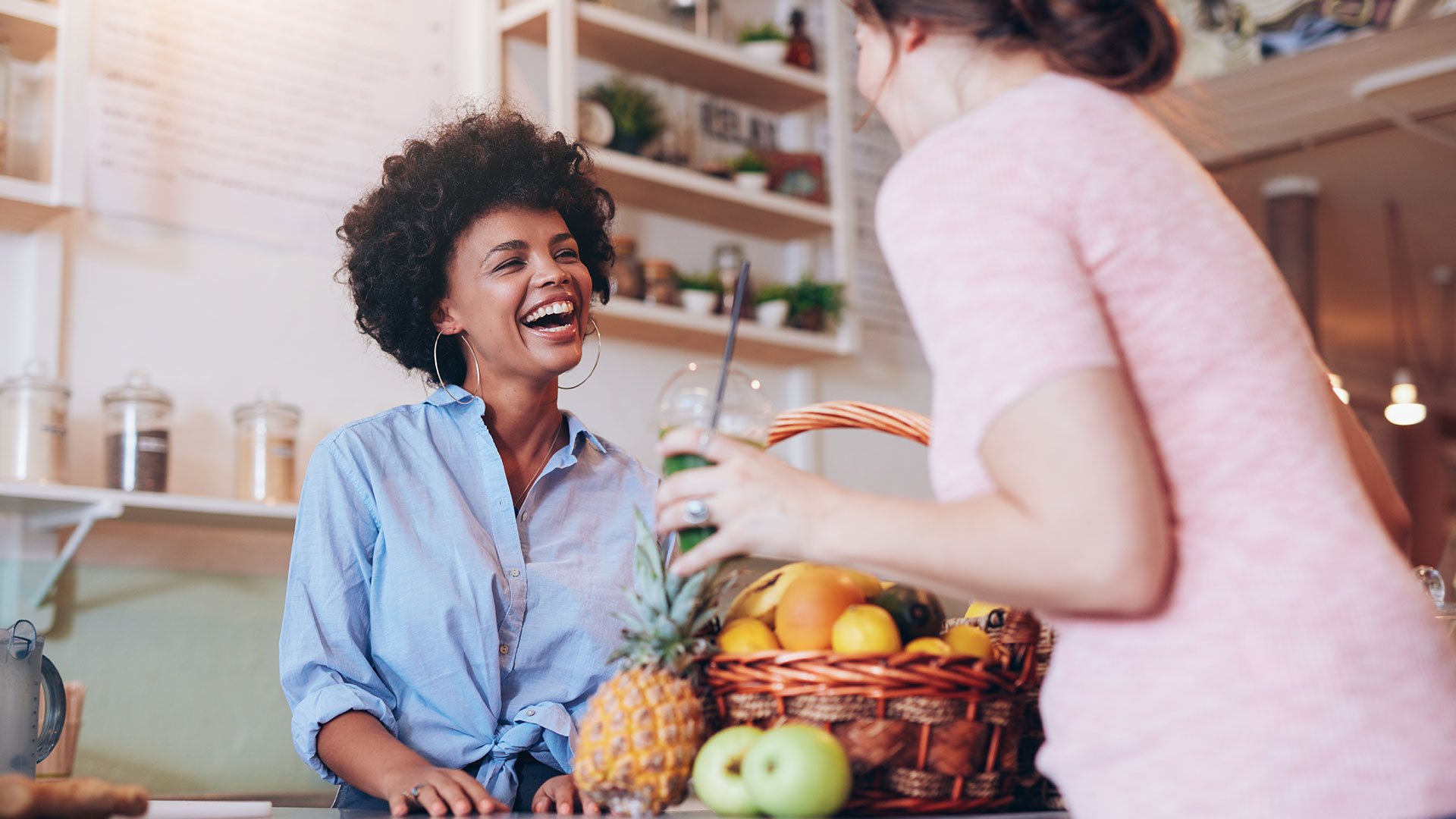 Female store owner smiling with client at checkout counter